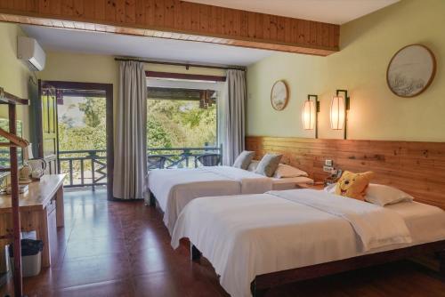a hotel room with three beds and a balcony at Snow Lion Riverside Resort in Yangshuo