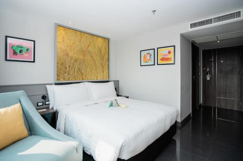 a hotel room with a bed and a chair at Garner Hotel Pattaya Central by IHG in Pattaya