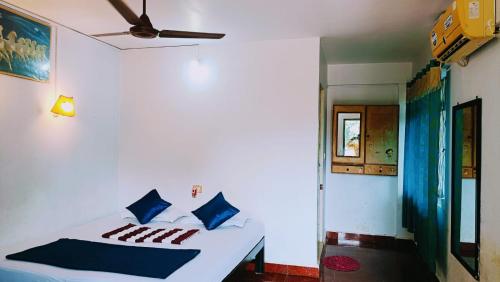 a bedroom with a white bed with blue pillows at JBL Guest House , Arombal , Goa in Arambol