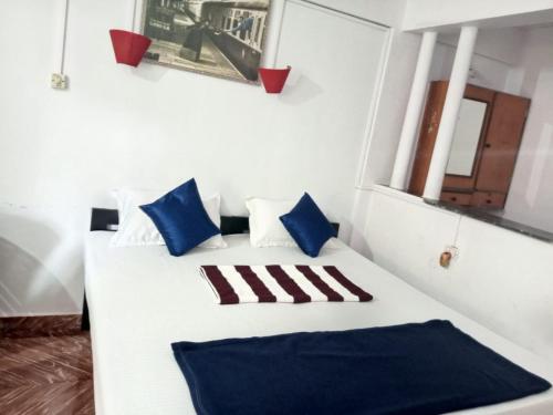 a bedroom with a white bed with blue pillows at JBL Guest House , Arombal , Goa in Arambol