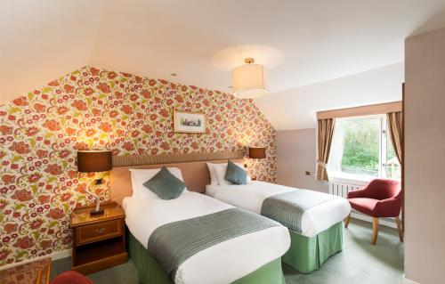 um quarto de hotel com duas camas e uma cadeira em The Stronlossit Inn em Fort William