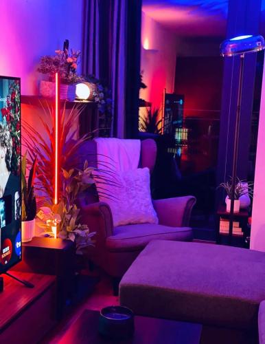 a living room with purple lighting and a couch at Advent House Ancoats Hosted Apartment in Manchester