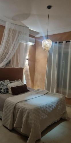 a bedroom with a bed and a chandelier at DAR-Layem in Hennchir Ksar Rhaleb