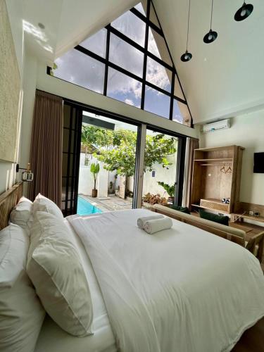 a bedroom with a large white bed with a large window at Gauri Vasanta Villa with Private Pool Yogyakarta in Yogyakarta