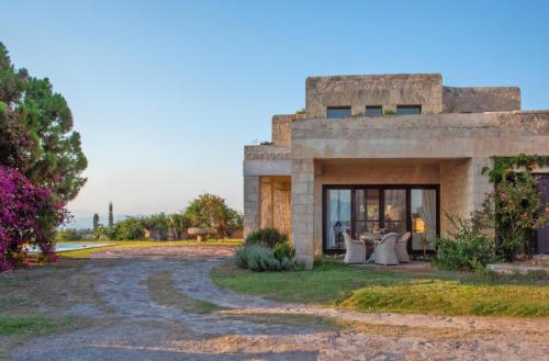 a stone house with a table and chairs outside at Majestique Villa Aegina in Egina