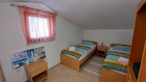 a small bedroom with two beds and a window at Apartment House Liznjan in Ližnjan