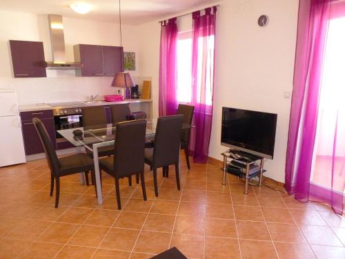 a dining room with a table and chairs and a television at Apartmani Kvesic - Azzurro in Šilo