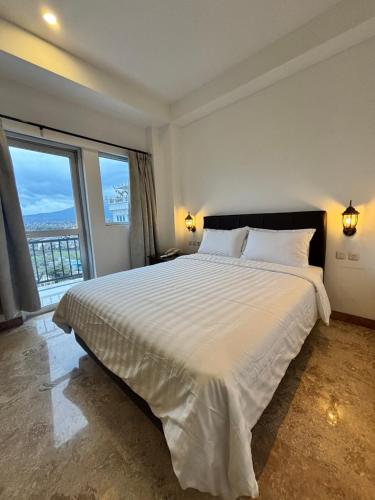 a bedroom with a large bed with a large window at Zam Hotel By Pavotel in Kedungbadak