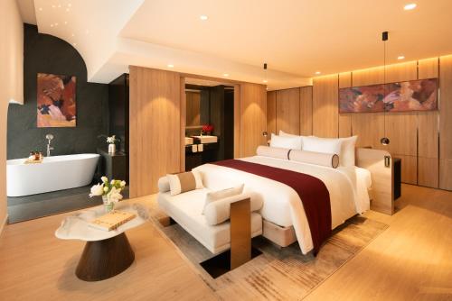 a bedroom with a large bed and a bath tub at The Auberg Collection Hotel in Ho Chi Minh City
