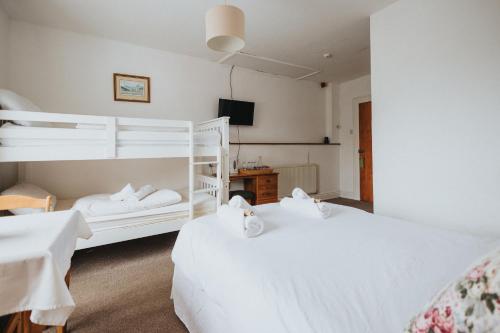 two beds in a hotel room with white beds at Y Pengwern in Ffestiniog