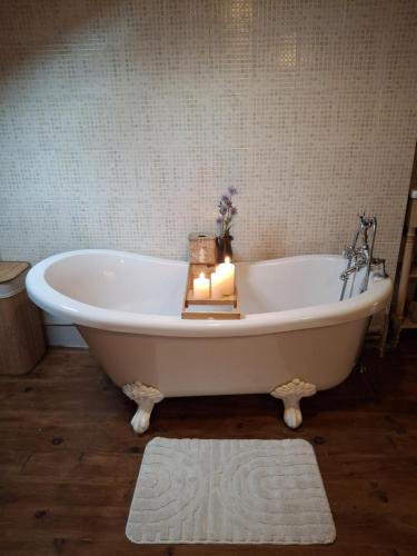 a white bath tub with a candle in a bathroom at L'Amour Toujours in Saint-Julien-le-Petit