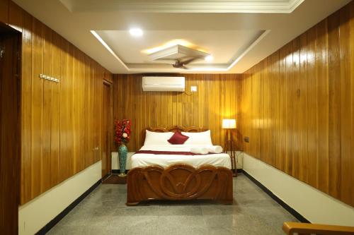 a bedroom with wooden walls and a bed in a room at SVS Grand in Dindigul