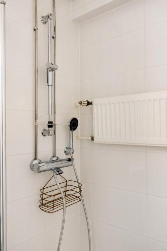 a shower in a bathroom with white tiles at Funky City Apartment By Lapland Host in Rovaniemi