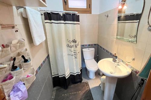 a bathroom with a toilet and a sink and a shower curtain at Finikas Garden Home in Karianí