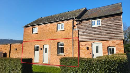 a brick house with two white doors on it at Gardeners Cottage Apartment in Tyberton
