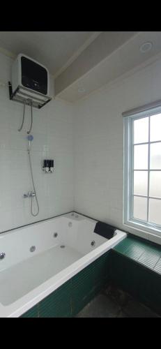 a white bath tub in a room with a window at Sukabumi Villa Mochi Private Jacuzzi in Sukabumi