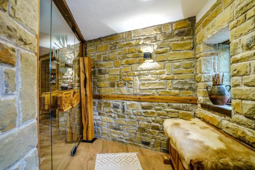 a room with a stone wall with a bench in it at Разбойна in Zheravna