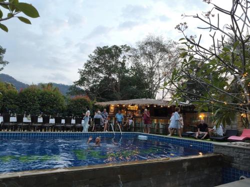 a group of people standing around a swimming pool at IYARA b in Ban Map Khangkhao