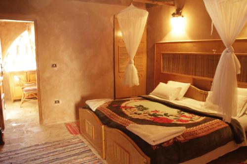 a bedroom with a bed and a dresser at Eskaleh Eco-Lodge in Abu Simbel