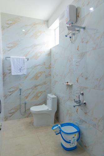 a white bathroom with a toilet and a shower at P V Grand in Dindigul