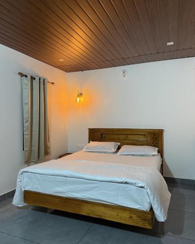 a bedroom with a large bed with a wooden ceiling at Pebbles in Thirunelli