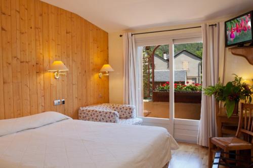 a bedroom with a bed and a window and a television at Hotel Restaurant de charme La Lozerette - Proche Florac in Cocurès