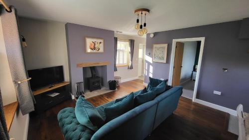a living room with a blue couch and a fireplace at Gardeners Cottage Apartment in Tyberton