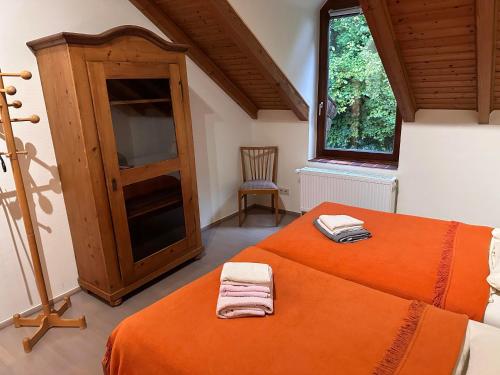 a bedroom with an orange bed and a window at Neumühle Saar in Mettlach