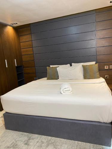 a large white bed in a room with a wall at Greyfield Apartment 1 in Benin City