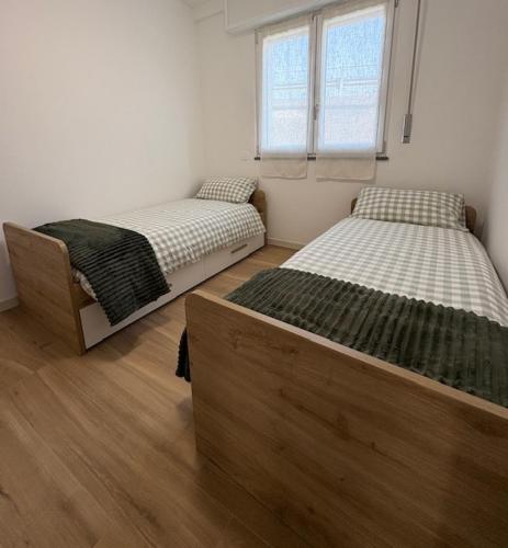 two twin beds in a room with wooden floors at LA CASETTA - Clusone in Clusone