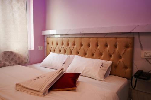 a bed with two white pillows and purple walls at P V Grand in Dindigul