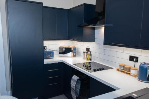 a kitchen with navy blue cabinets and a microwave at The White House near Edinburgh in Bathgate