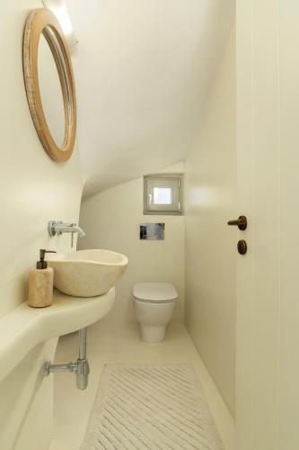 a white bathroom with a sink and a toilet at West Side Pool House by Hostandros in Gavrio