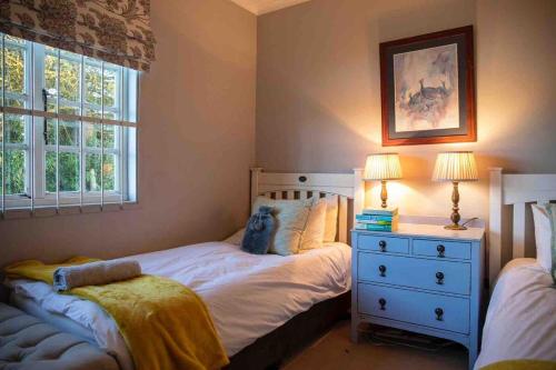 a bedroom with two beds and a dresser and a window at Lake Zonk Cottage in Mooiriver