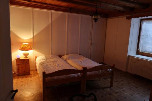 a bedroom with a bed and a lamp and a window at Ferme en pleine nature in Boudevilliers