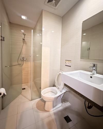 a bathroom with a toilet and a sink and a shower at Henry's Newport Condotel in Manila