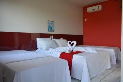 a hotel room with two beds and a red wall at Pousada Tropical in Prado