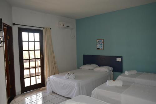 a bedroom with two beds with white sheets and a window at Pousada Tropical in Prado