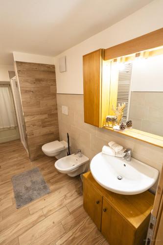 a bathroom with two sinks and a toilet and a mirror at Appartamenti dei Maerins in Pozza di Fassa