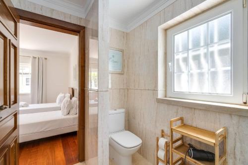 a bathroom with a toilet and a window at Grande Villa com Piscina Privada | Ericeira in Ericeira