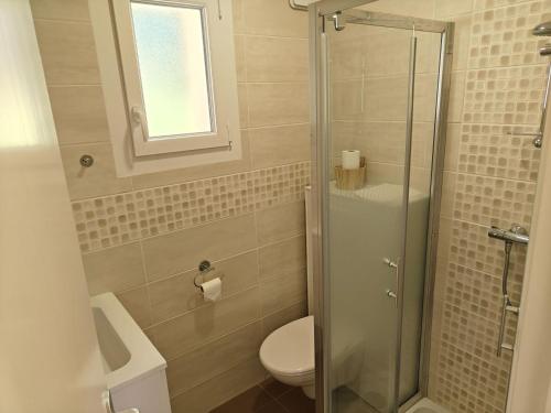 a bathroom with a toilet and a glass shower at Studios - Location de vacances Le Trécelin in Plévenon