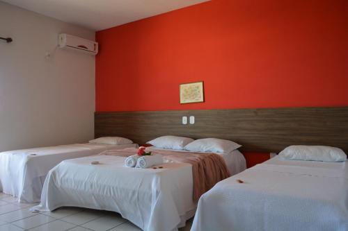 Habitación con 2 camas y pared de color naranja. en Pousada Tropical, en Prado