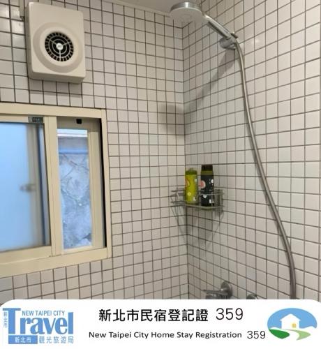 a shower in a bathroom with a white tiled wall at Shan Cheng Guesthouse in Ruifang