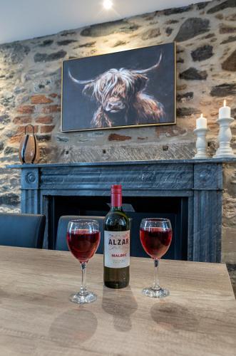 a bottle of wine sitting on a table with two glasses at Castle Street Apartments - Luxury Scalpsie Apartment in Rothesay