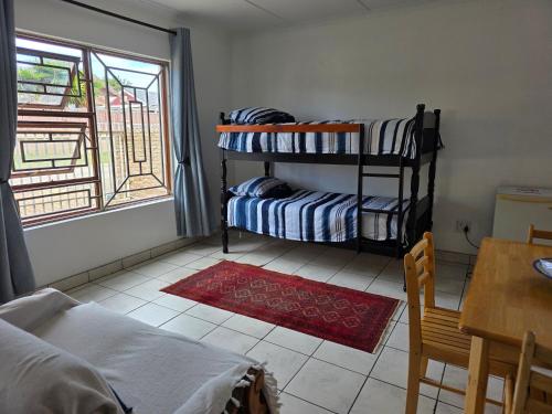 a room with two bunk beds and a table and a window at Driftwood Haven in Mossel Bay