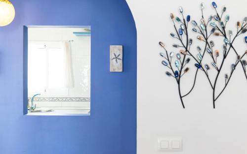 a bathroom with a blue wall with a painting of a tree at Sirius in La Isleta del Moro