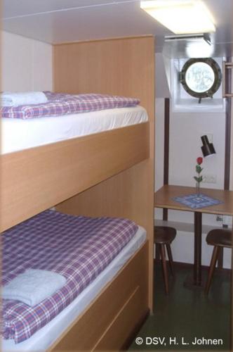 a room with two bunk beds and a table with a clock at Schulschiff Deutschland Bremerhaven in Bremerhaven