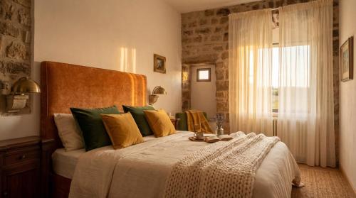 a bedroom with a large bed with green and yellow pillows at Roberto Historic House in Gubbio