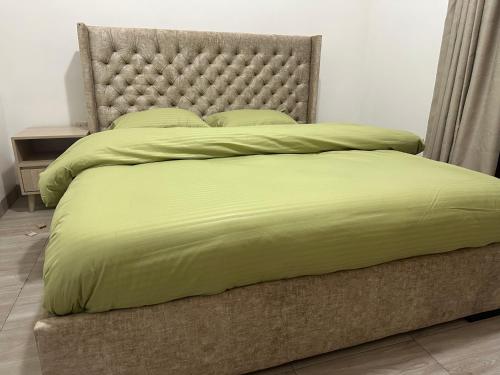 a large bed with a green comforter and pillows at Dash-8 in Kigali