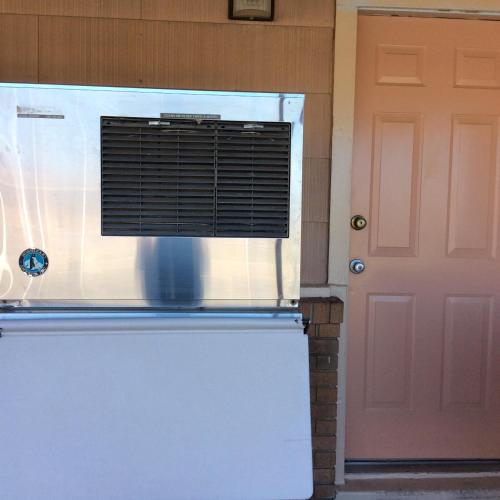a white refrigerator with a window next to a door at Regency Inn Comanche in Comanche